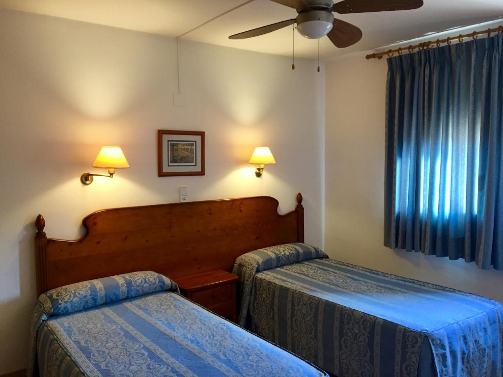 a hotel room with two beds and a ceiling fan at Casa Emilio in Torre Baja