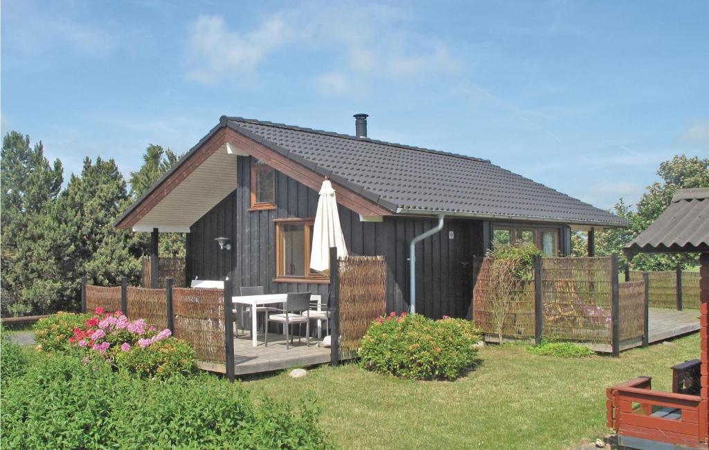 una pequeña casa negra con una mesa y una sombrilla en Cozy Home In Vordingborg With House A Panoramic View en Næs