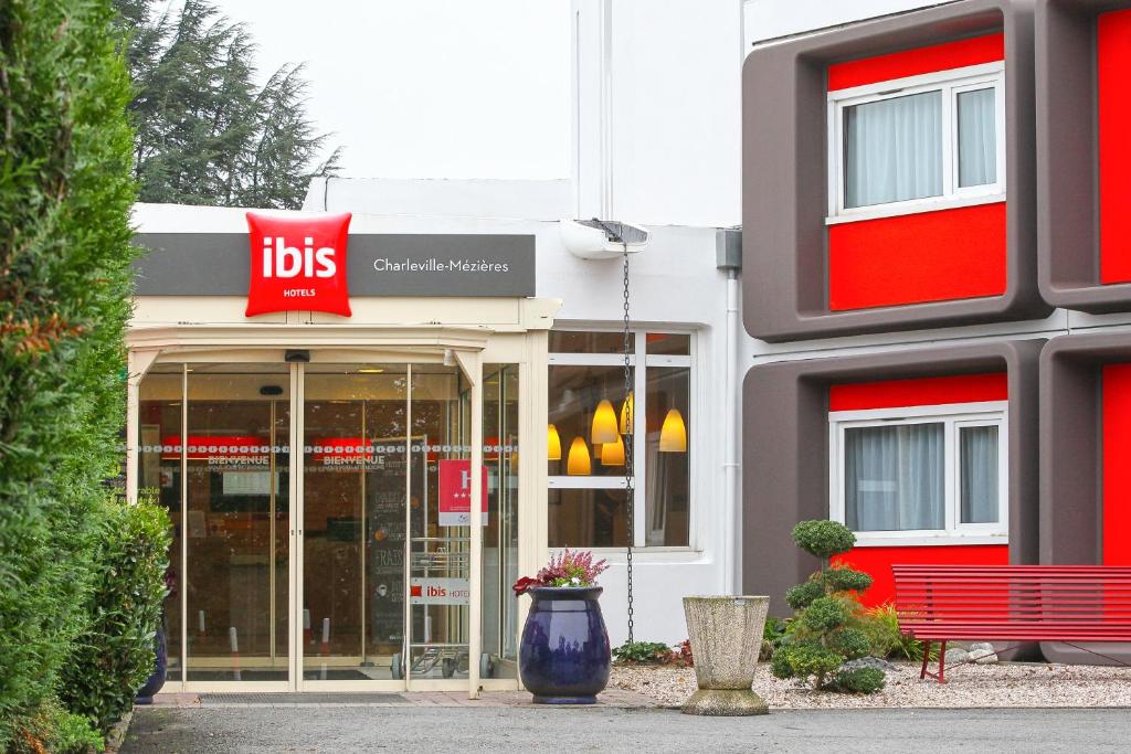 un negozio con un cartello rosso sul lato di un edificio di ibis Charleville Mézières a Villers-Semeuse