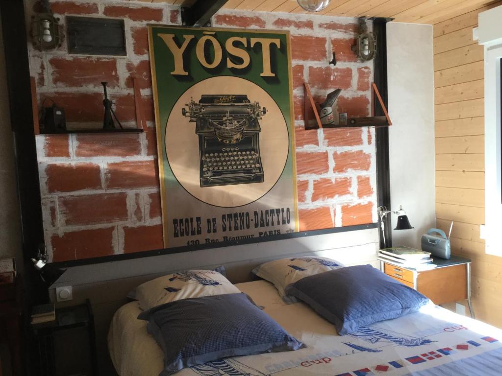 ein Poster über einem Bett in einem Zimmer mit Ziegelwand in der Unterkunft La Maison de Jean in Les Adrets
