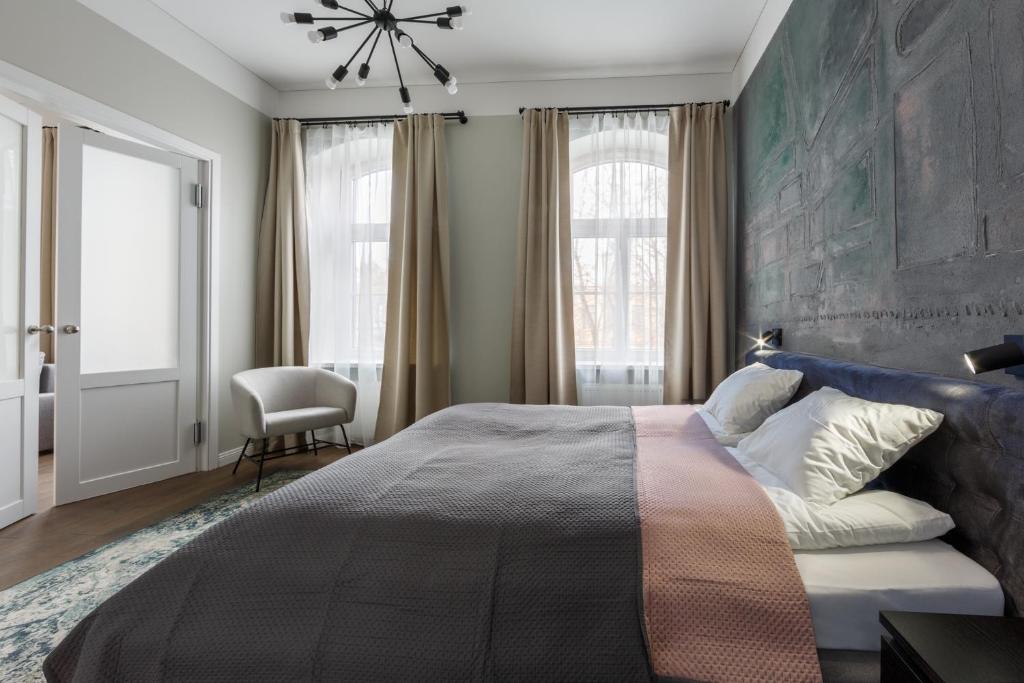 a bedroom with a large bed and a chair at Laisves ave. Apartments in Kaunas