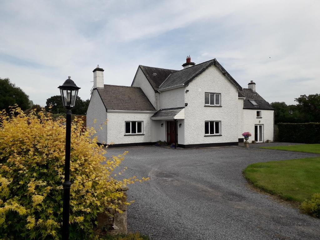 uma casa branca com uma luz de rua em frente em Wellfield Farmhouse em Tipperary