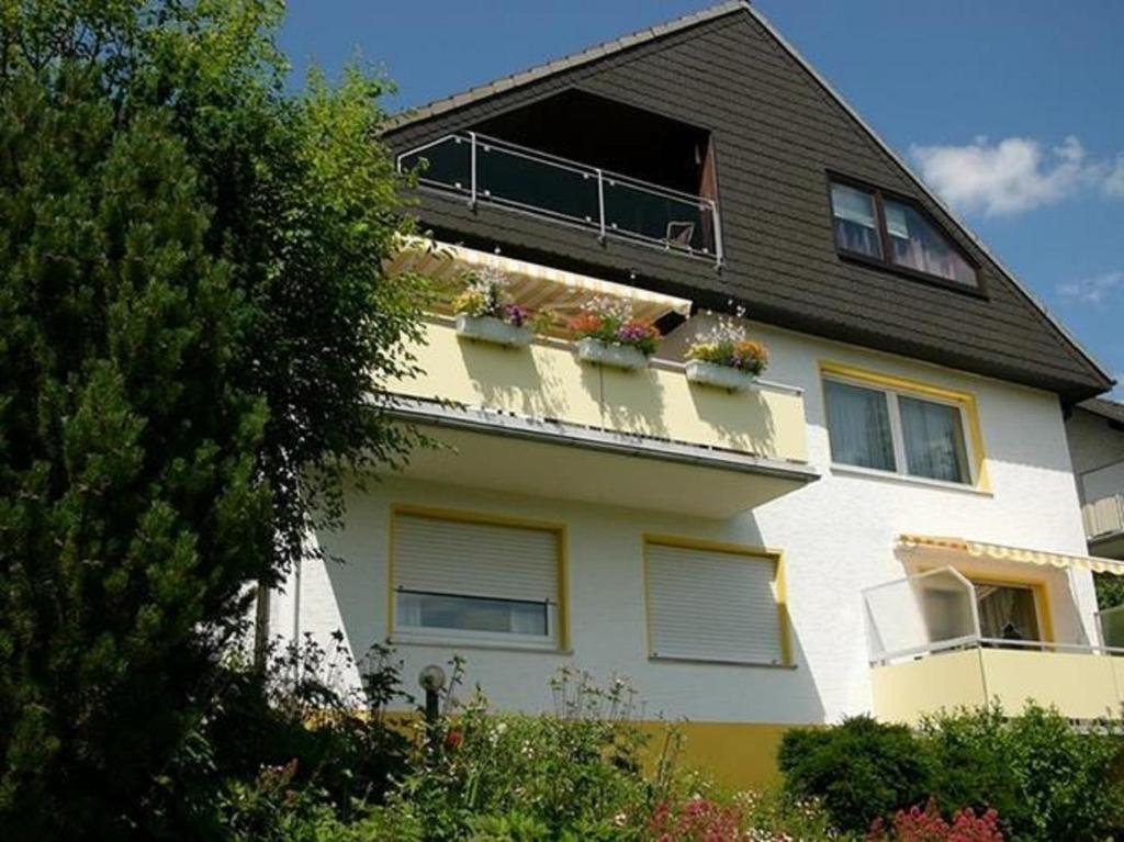 ein weißes Gebäude mit einem Balkon mit Topfpflanzen darauf in der Unterkunft Ferienwohnungen Luttmann Ausblick pur in Bad Pyrmont