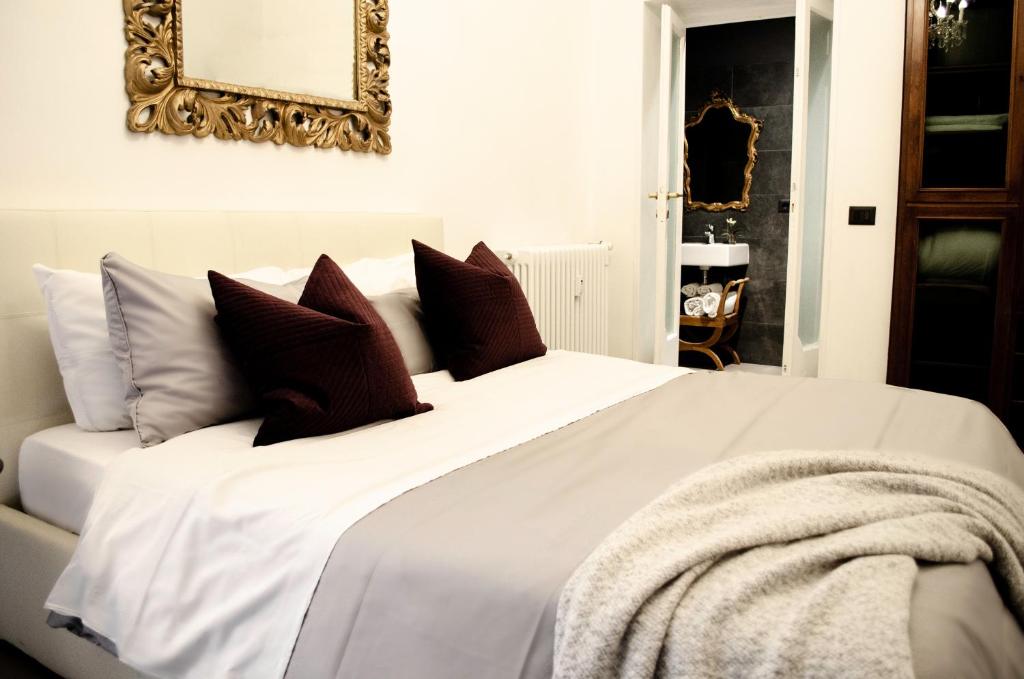 cama blanca con almohadas y espejo en la pared en Apartment via Ferrucci 22, en Milán