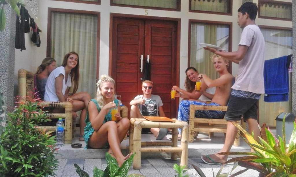 un grupo de personas sentadas en bancos frente a una casa en Pondok Linda, en Gili Trawangan