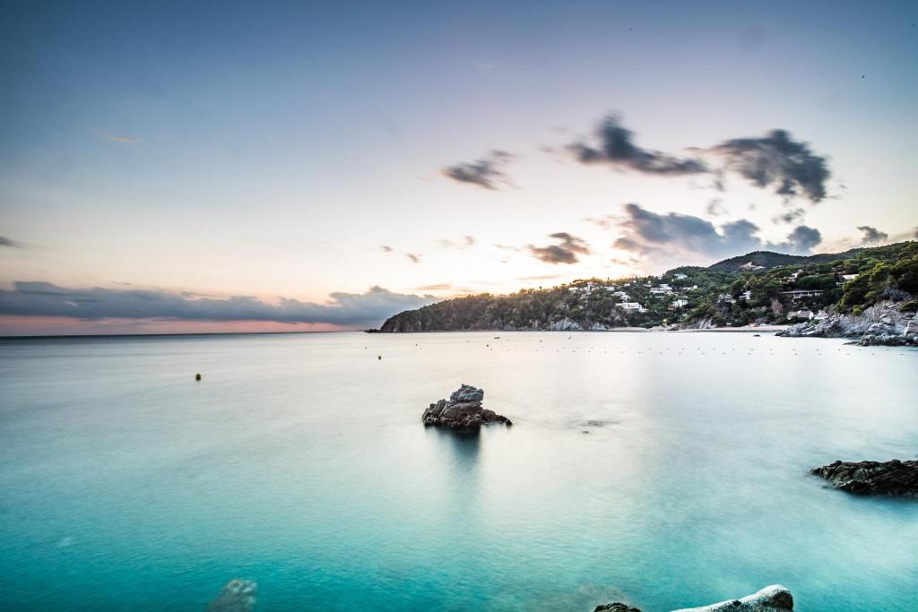 vistas a una playa con una roca en el agua en Camping Cala Llevado, en Tossa de Mar
