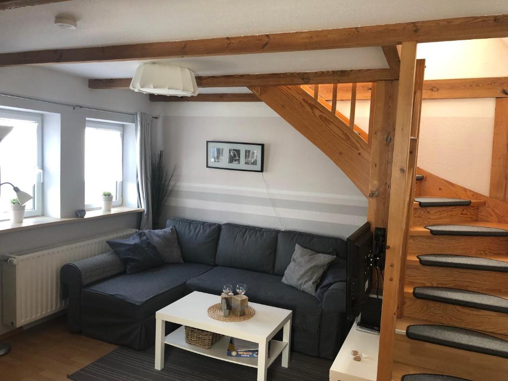 ein Wohnzimmer mit einem blauen Sofa und einer Treppe in der Unterkunft Gästehaus Kantelberg in Dahme