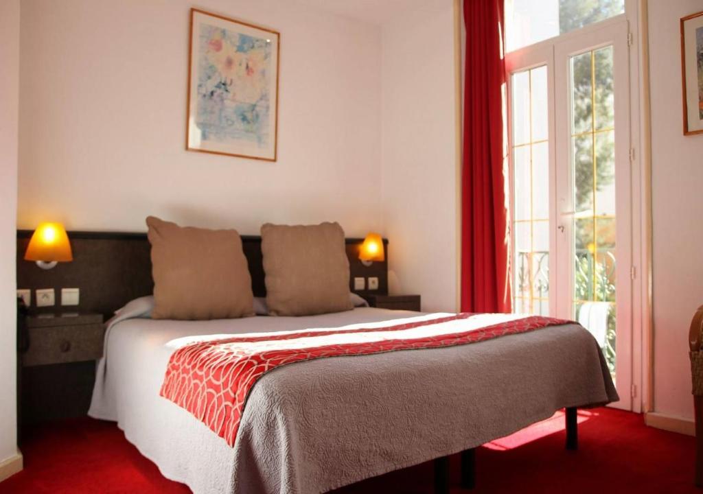 a bedroom with a bed with a red carpet at Hôtel restaurant Oasis in Nice