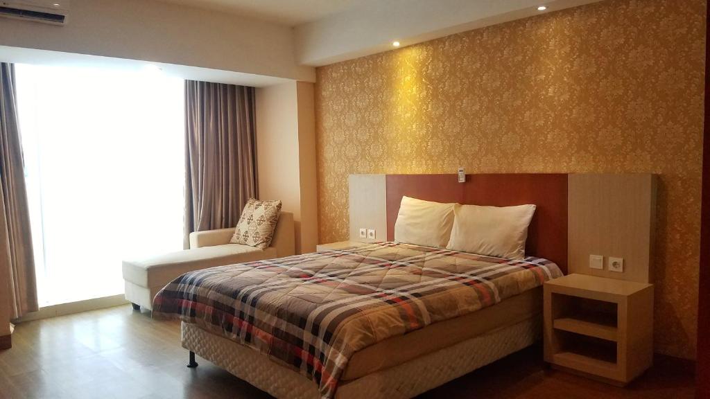 een hotelkamer met een bed en een stoel bij Lavenderbnb Room 10 at Mataram City Apartment in Yogyakarta