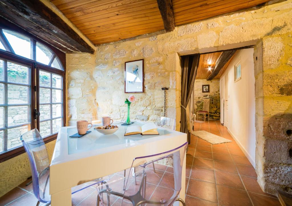une cuisine avec une table et des chaises dans un mur en pierre dans l'établissement Au coeur de l'un des plus beaux villages de France, à Beynac-et-Cazenac