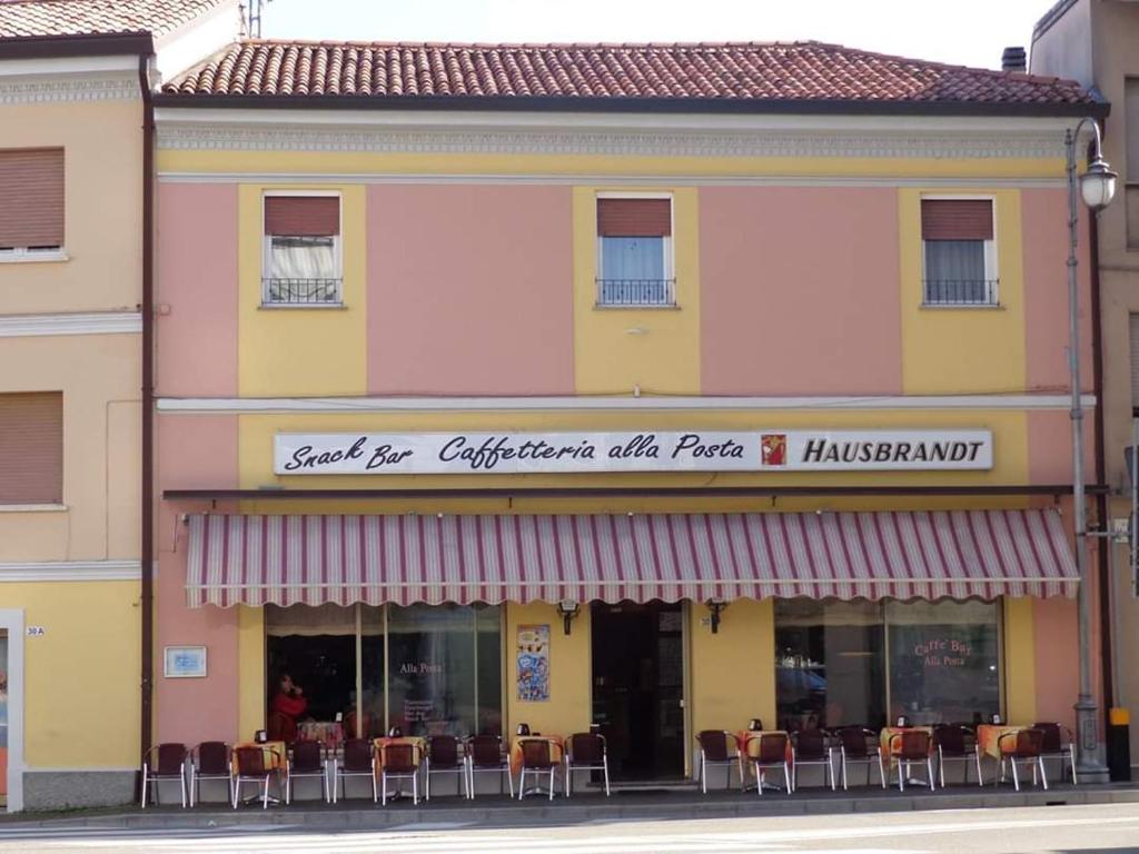 restauracja ze stołami i krzesłami przed budynkiem w obiekcie Hotel Affittacamere alla Posta w mieście San Giórgio di Nogaro