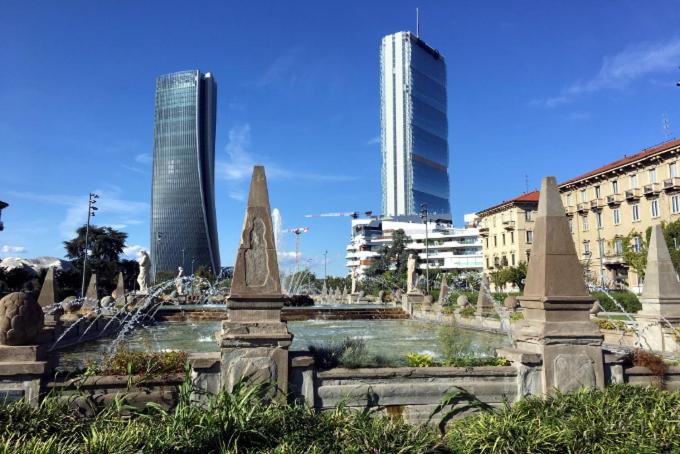 una fontana nel mezzo di una città con edifici alti di Welcome Home a Milano