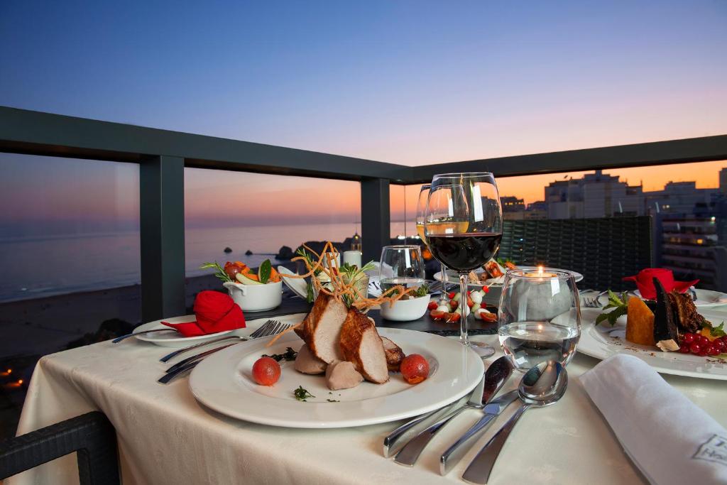 a table with plates of food and glasses of wine at RR Hotel da Rocha in Portimão