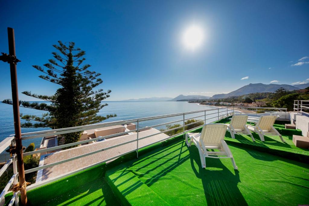 una fila di sedie su un balcone affacciato sull'acqua di Appartamento 16 Pax in Villa Francesca Sicily sul mare a Casteldaccia