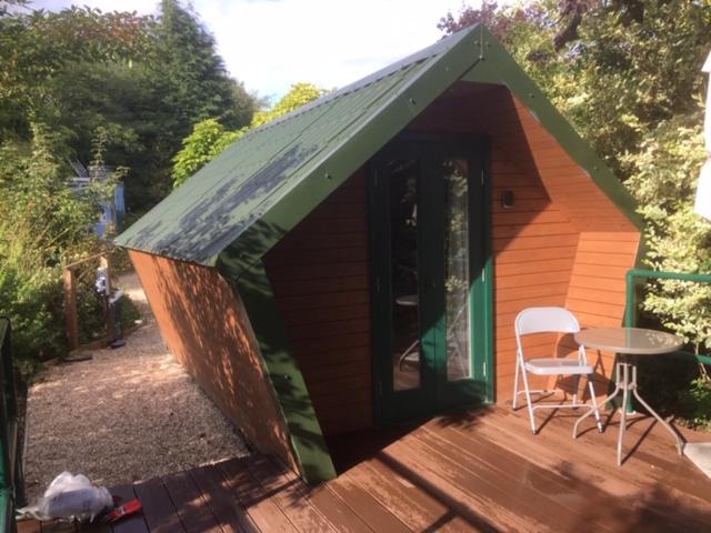 ein kleines Haus mit einem Tisch und einem Stuhl auf einer Terrasse in der Unterkunft Lodge in Yeovil