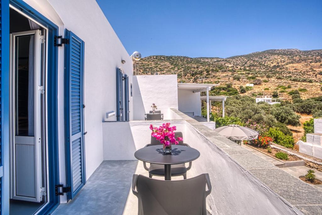 a table on the balcony of a house with flowers at SifnosLiving A1 in Vathi