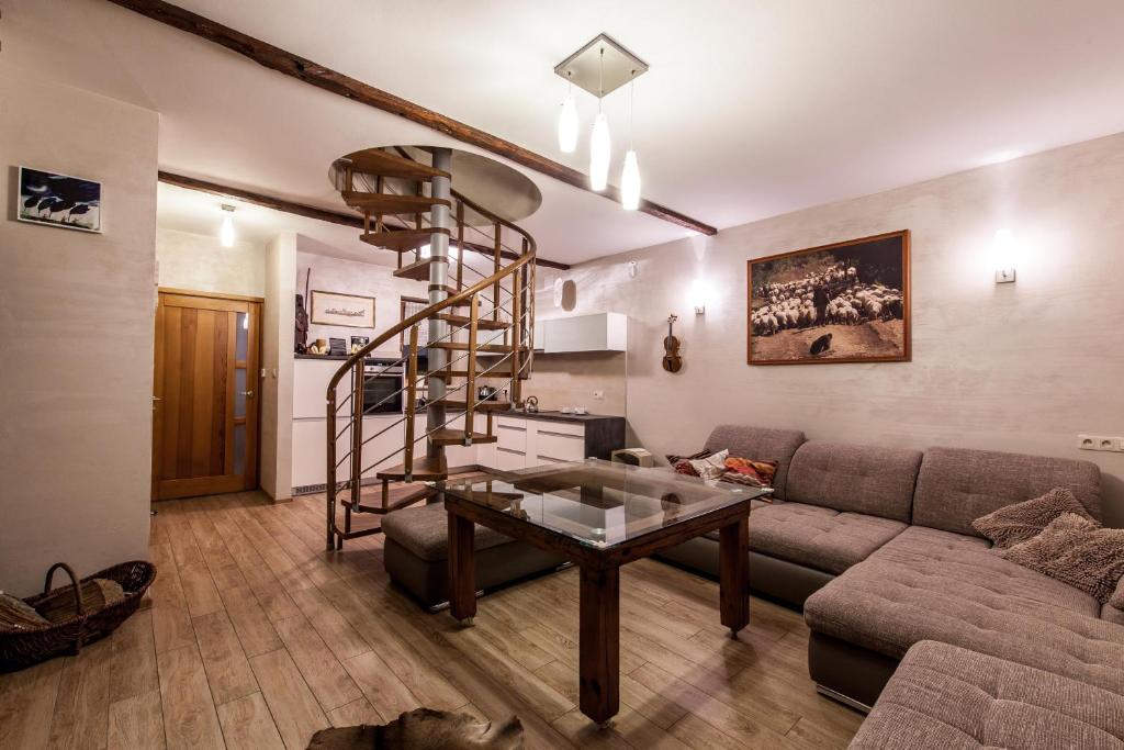 a living room with a couch and a spiral staircase at APARTAMENT NA SZLAKU in Szczawnica