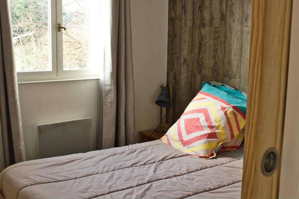 um quarto com uma cama com uma almofada e uma janela em Gite rural Herbignac - La Roche Bernard em Herbignac