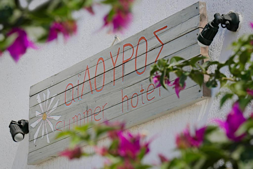 una señal en el lado de un edificio con flores en Ailouros summer hotel en Skhoinoussa