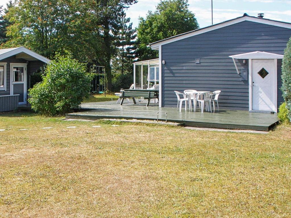 a house with a deck with chairs and a picnic table at Holiday home Væggerløse LXII in Marielyst