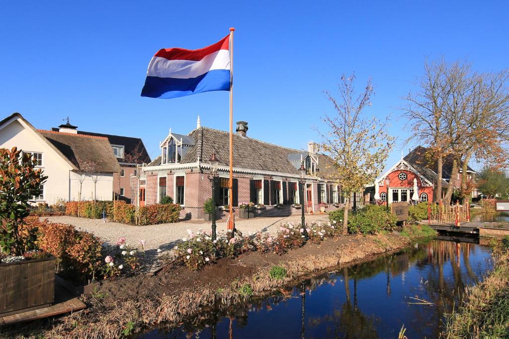 a flag flying in front of a house next to a river at Small Luxury Boutique Hotel Wilma J in Vinkeveen