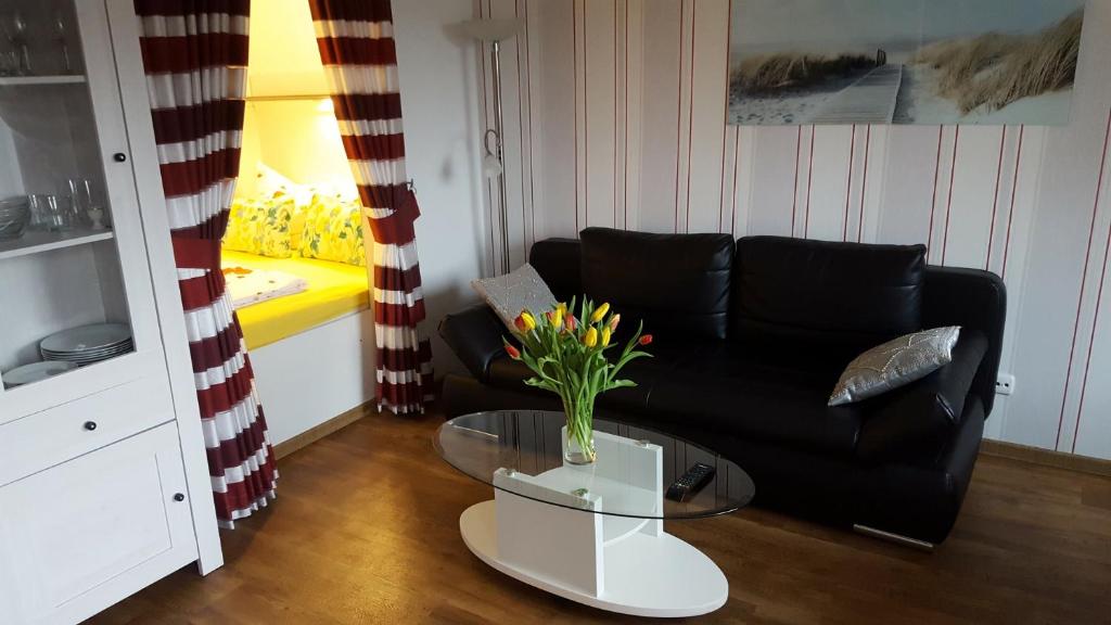 uma sala de estar com um sofá preto e uma mesa de vidro em Geeste 2 em Bremerhaven