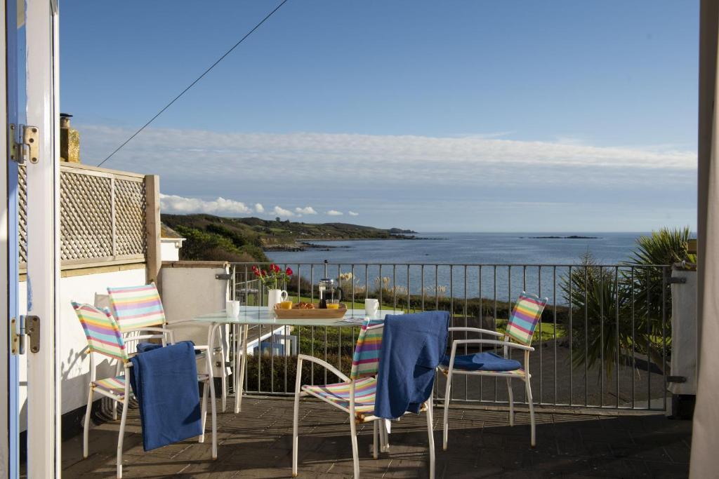 a balcony with a table and chairs and the ocean at Little Trevara, Marazion in Marazion