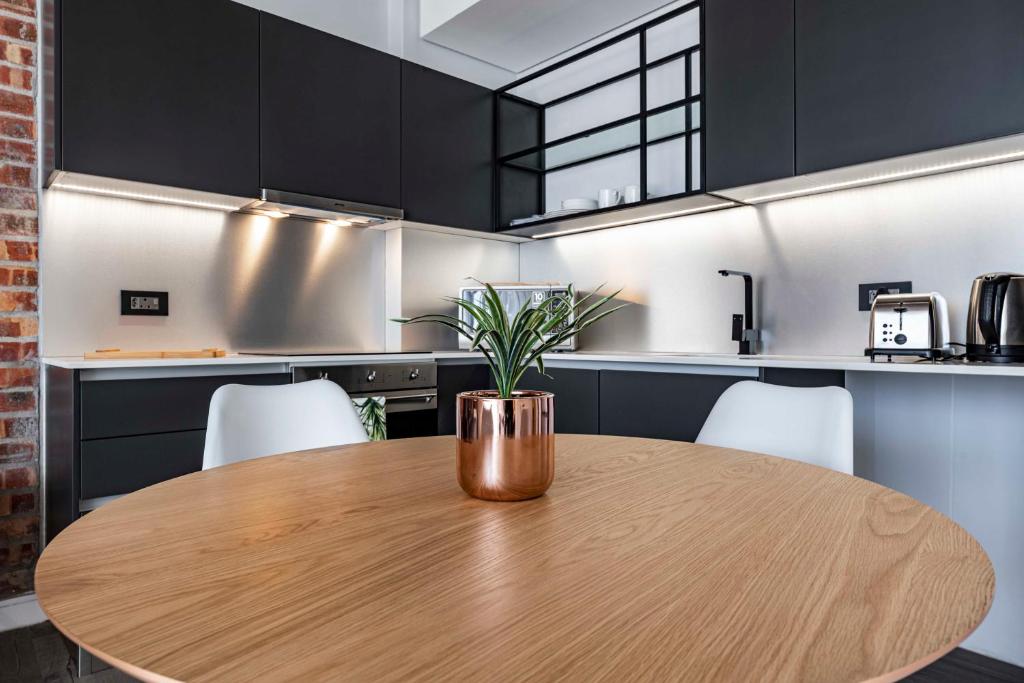 einem Holztisch mit einer Topfpflanze in der Küche in der Unterkunft 402 The Signature, De Waterkant in Kapstadt