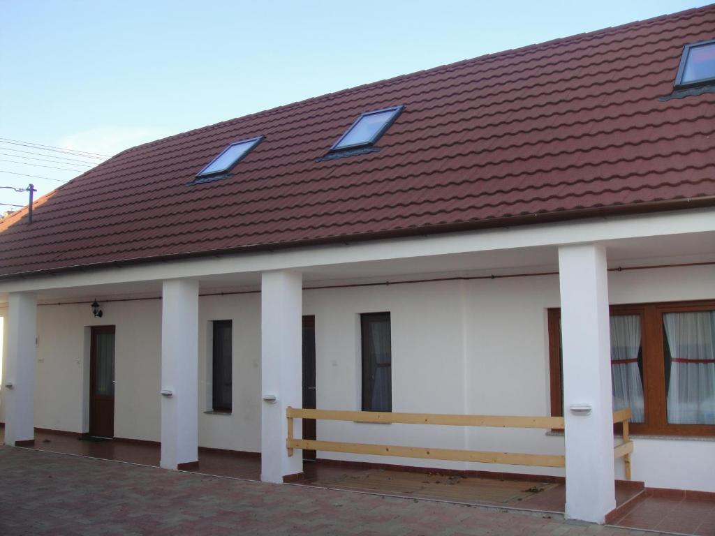 un edificio blanco con techo marrón y banco en Paks Panzió en Paks
