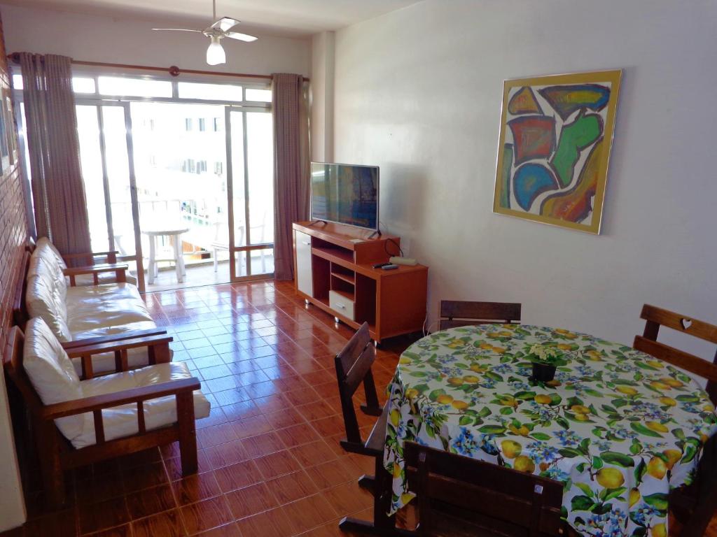uma sala de estar com uma mesa e uma televisão em Apartamento praia do forte em Cabo Frio