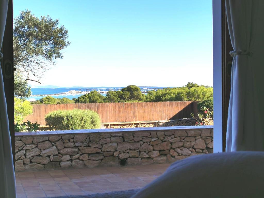 a view of a stone wall from a bedroom window at VILLA BELLA VISTA in Sant Francesc Xavier