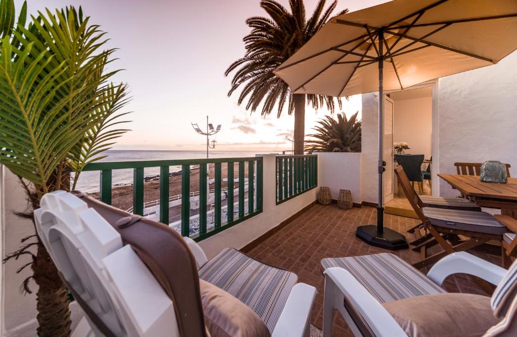 a balcony with chairs and an umbrella and the ocean at Luxury Suite Sea Front in Playa Honda