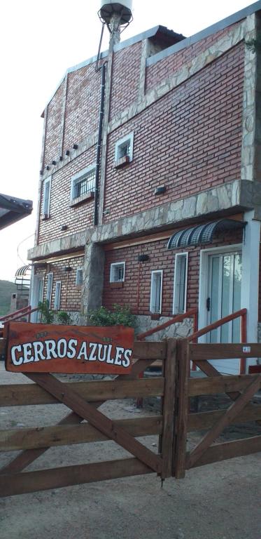 una valla de madera frente a un edificio de ladrillo en Cerros Azules en Trapiche