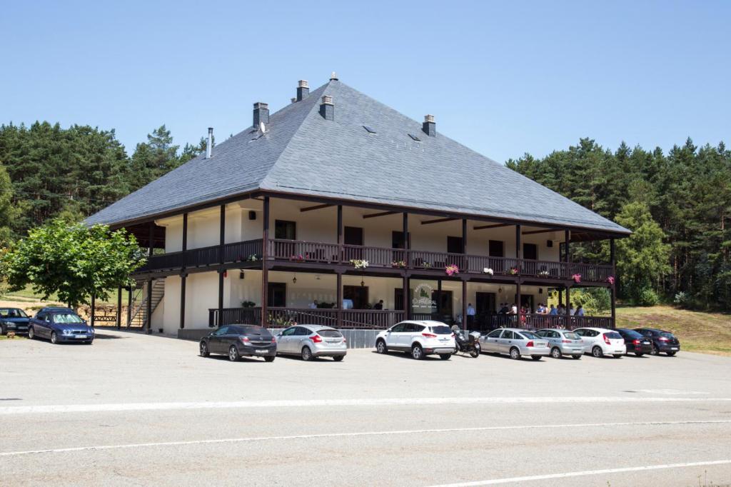 ein großes Gebäude mit Autos auf einem Parkplatz in der Unterkunft Albergue Piñeiral Fonsagrada in A Fonsagrada