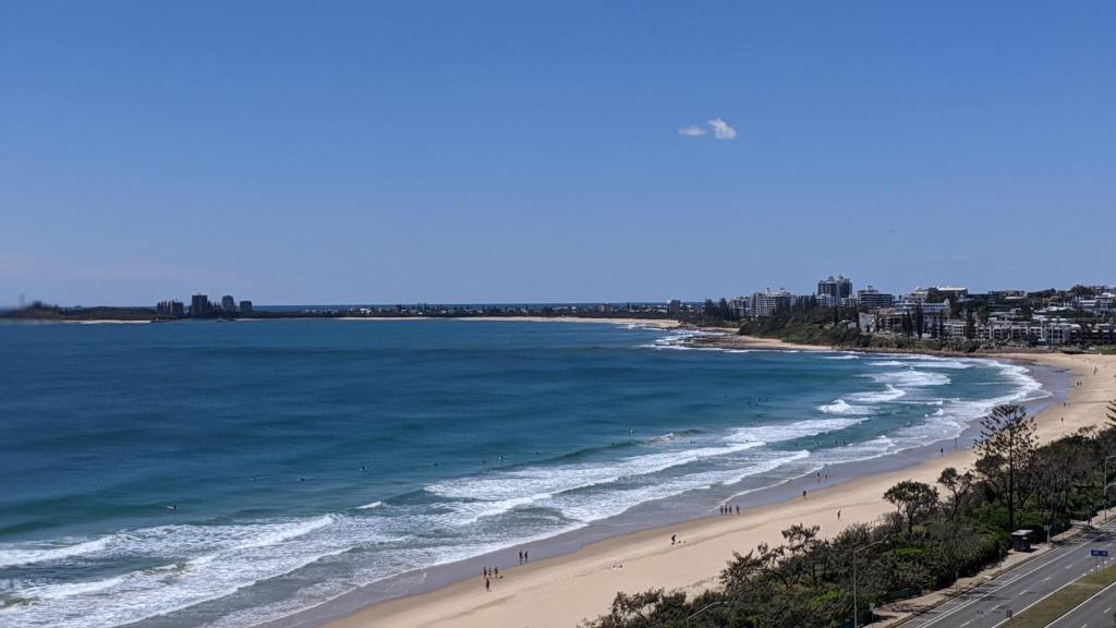 a beach with people walking on the sand and the ocean at Beachfront Towers in Maroochydore