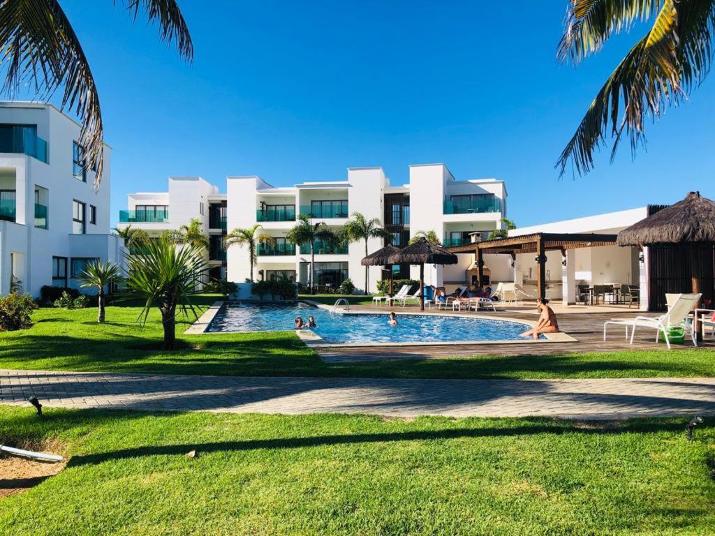 a swimming pool in front of a large building at O Paraíso que você merece in Praia do Forte