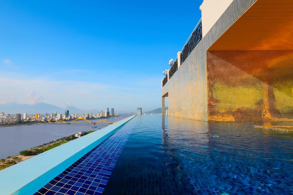 A rooftop infinity pool runs along the building beside a wide river panorama.