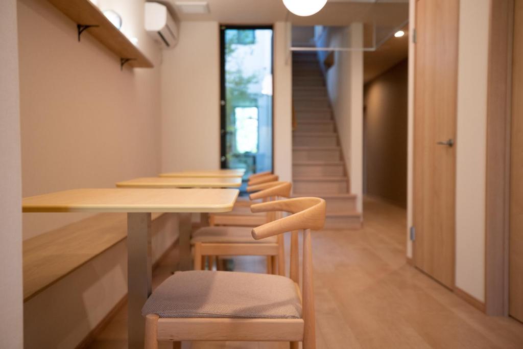 a room with a table and chairs and a staircase at Onya Kaede in Kyoto