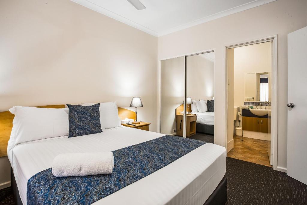 a bedroom with a large bed and a bathroom at Karratha Central Apartments in Karratha