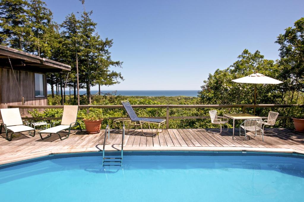 a swimming pool with chairs and a table and an umbrella at The Eliot Noyes in Chilmark