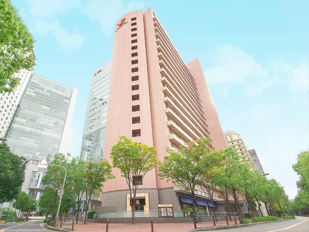 大阪的住宿－西梅田哈頓酒店，一座高大的粉红色建筑,前面有树木