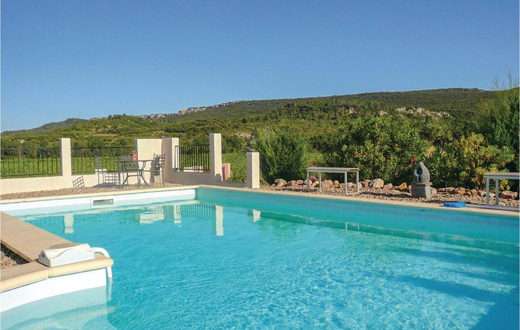 a large blue swimming pool with a mountain in the background at Beautiful Home In Prades Sur Vernazobre With Outdoor Swimming Pool in Prades-sur-Vernazobre