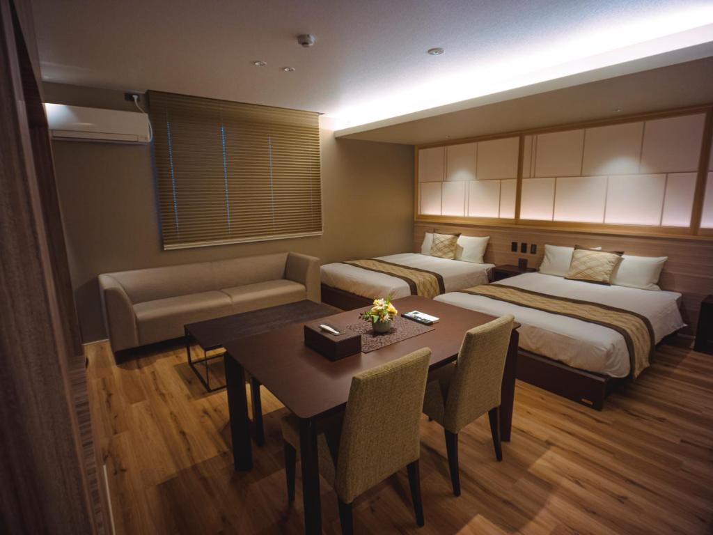 una camera d'albergo con due letti e un tavolo con sedie di GRAND BASE Beppueki a Beppu