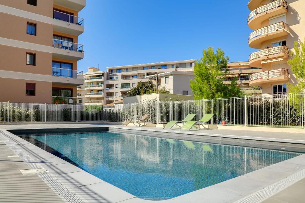 une piscine avec deux chaises et un bâtiment dans l'établissement Appartement Danaé Antibes, à Antibes