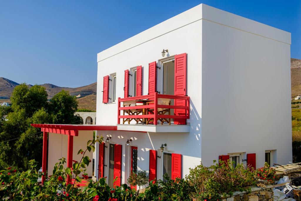 un edificio blanco con ventanas rojas y persianas rojas en Sea View Villa, en Megas Gialos - Nites