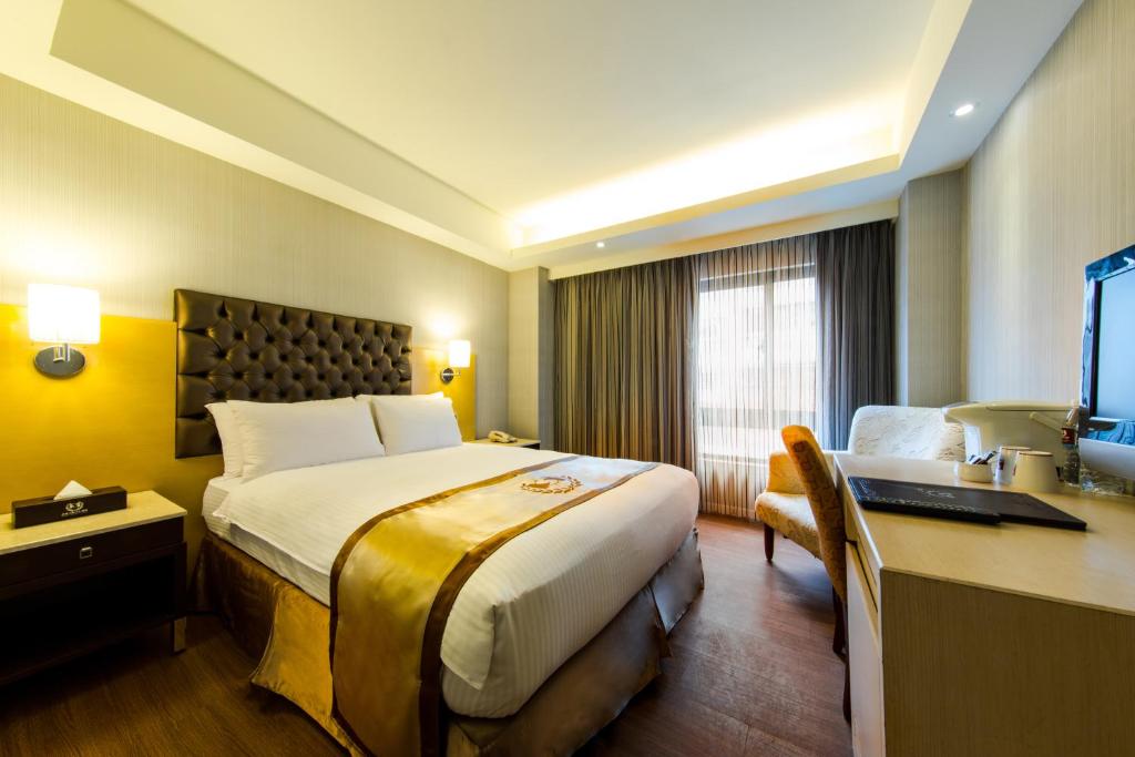 um quarto de hotel com uma cama e uma secretária com um computador em HopeCity MinSheng Hotel em Taipei