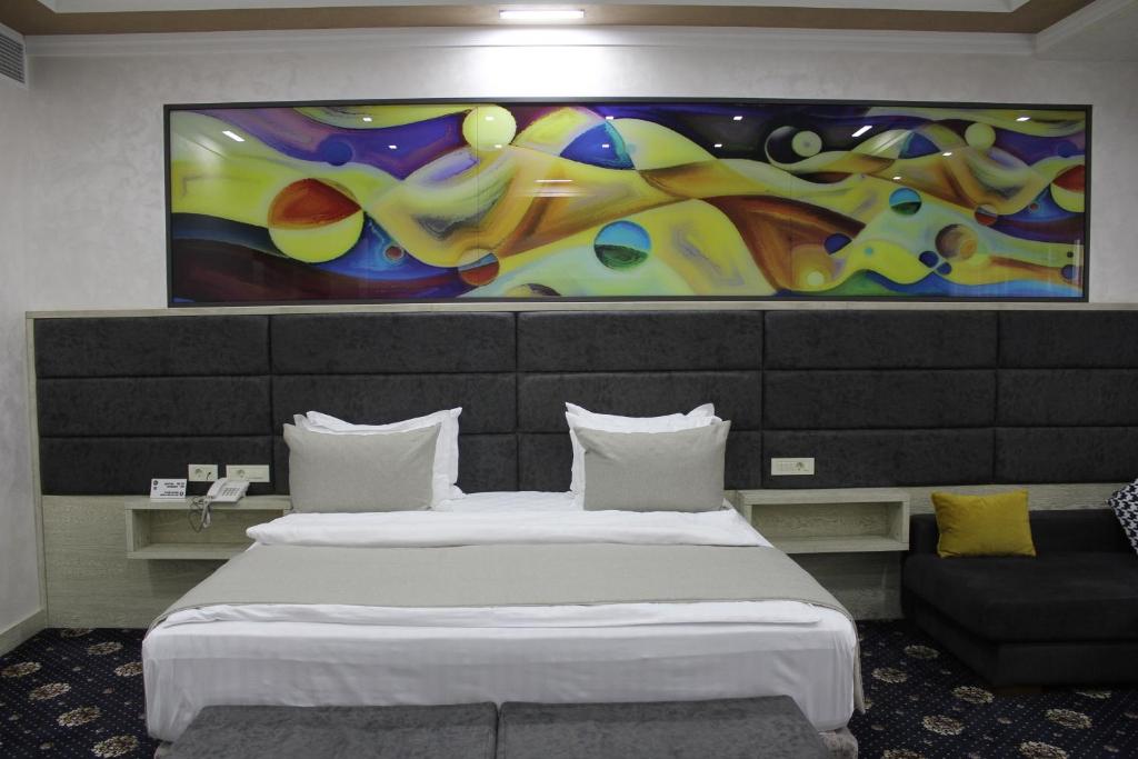 エレバンにあるErebuni Hotel Yerevanのベッド2台が備わる客室で、壁には絵画が飾られています。