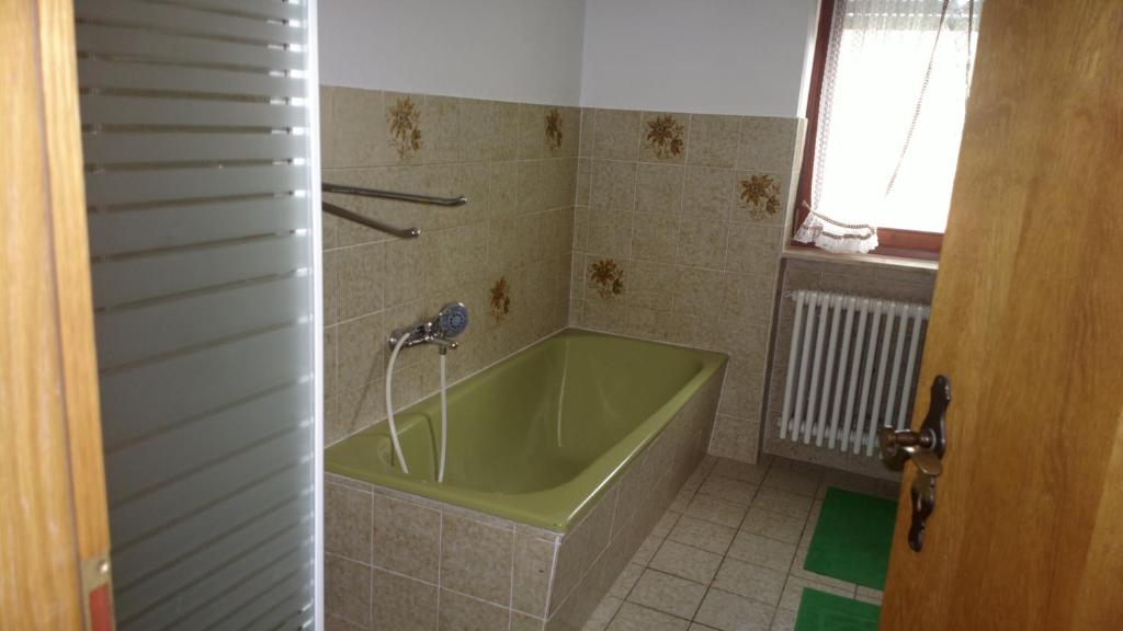 La salle de bains est pourvue d'une baignoire verte et d'une fenêtre. dans l'établissement Ferienhaus Frankenhöhe, à Diebach