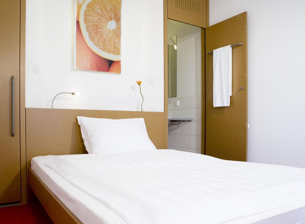 a bedroom with a white bed and a bathroom at Orange Wings Wiener Neustadt in Wiener Neustadt
