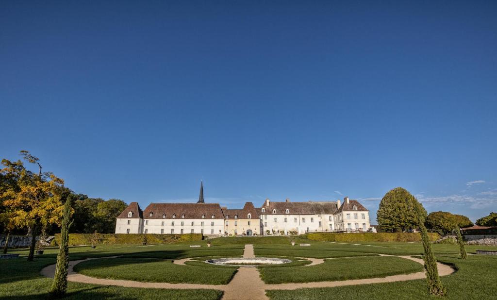 a large building with a fountain in the middle of a park at Château de Gilly in Vougeot